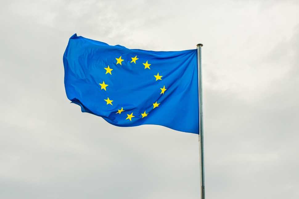 Bandeira da União Europeia com o céu cinzento no fundo. Representa bolsas da Europa