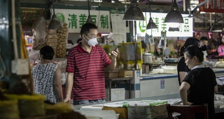 Um comprador usou seu telefone celular para fazer um pagamento digital em um mercado úmido em Xangai. [Fonte: Qilai Shen/Bloomberg News]